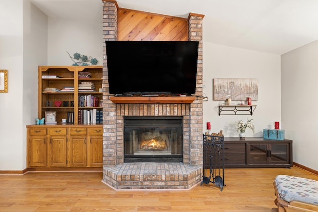 living room with a brick fireplace, vaulted ceiling, and light wood-type flooring