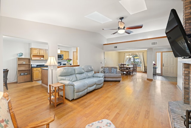 living room with lofted ceiling with skylight, ceiling fan, and light hardwood / wood-style flooring