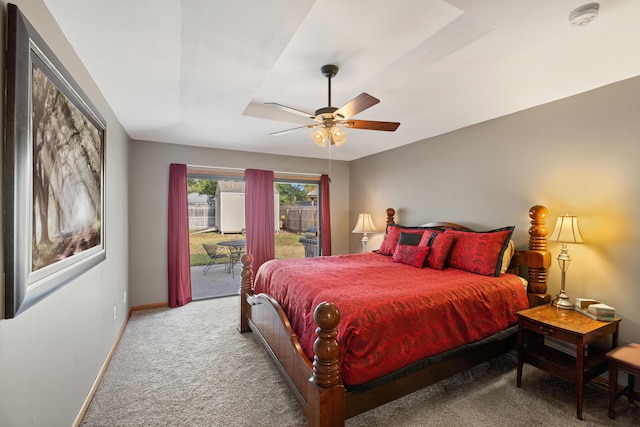 carpeted bedroom with ceiling fan, a tray ceiling, and access to exterior