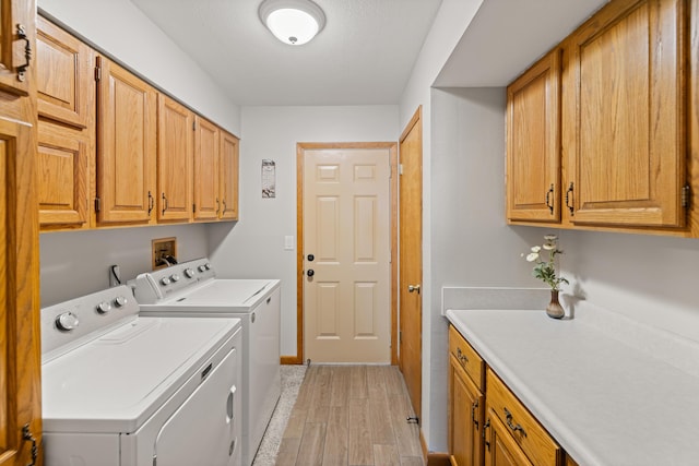 laundry area featuring cabinets, light hardwood / wood-style floors, and washing machine and dryer