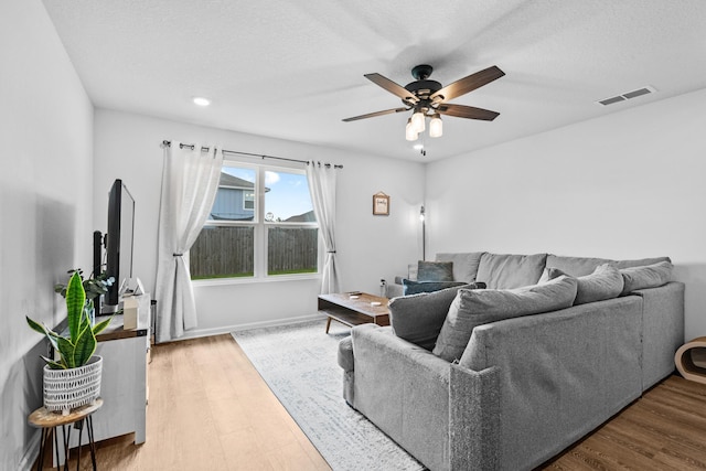 living room featuring ceiling fan, hardwood / wood-style floors, and a textured ceiling