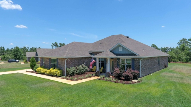 view of front facade with a front lawn, a shingled roof, and brick siding