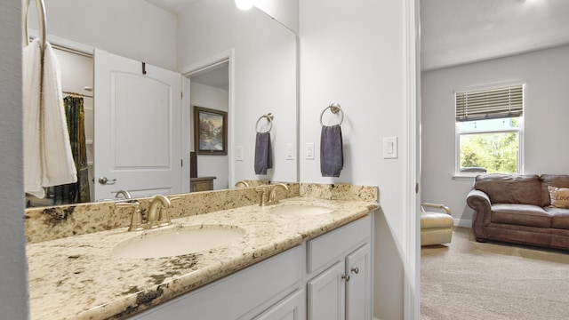 bathroom featuring connected bathroom, a sink, baseboards, and double vanity