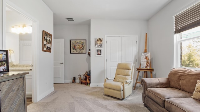 living area with baseboards, visible vents, and light colored carpet