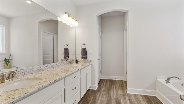 full bathroom featuring a garden tub, a sink, baseboards, and wood finished floors