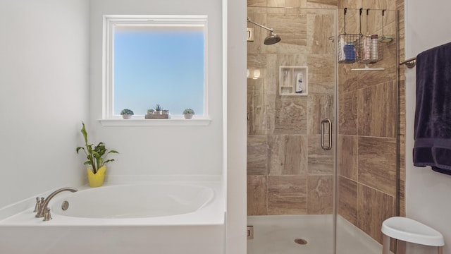 bathroom featuring a stall shower and a bath