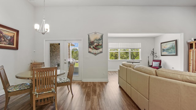 dining space featuring baseboards, a chandelier, wood finished floors, and french doors