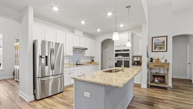 kitchen with white cabinetry, stainless steel appliances, sink, and an island with sink