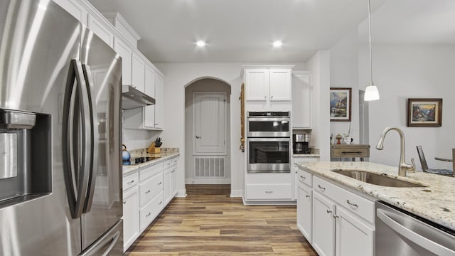 kitchen with white cabinets, under cabinet range hood, stainless steel appliances, and a sink