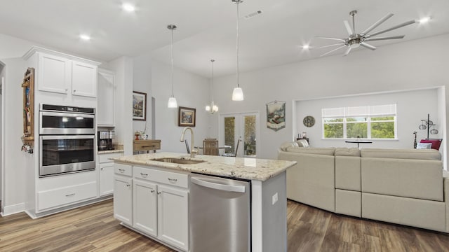 kitchen featuring a center island with sink, open floor plan, wood finished floors, stainless steel appliances, and a sink