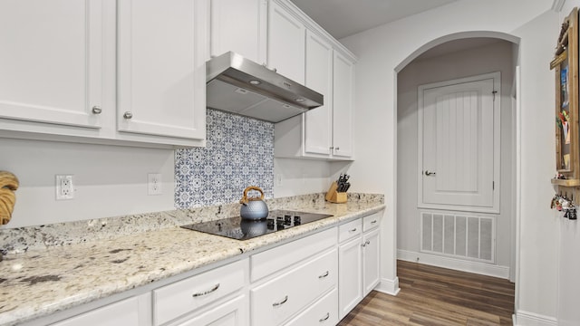 kitchen featuring visible vents, white cabinetry, ventilation hood, wood finished floors, and black electric cooktop