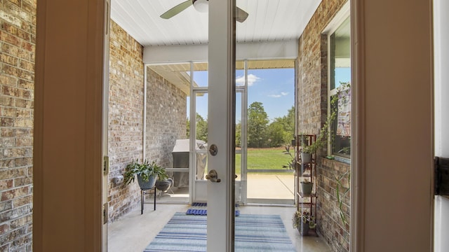 entryway with concrete flooring, brick wall, and a ceiling fan