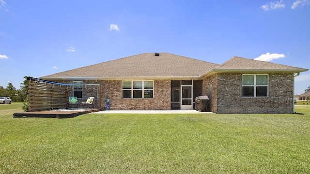 rear view of property with roof with shingles, a patio, a lawn, and brick siding