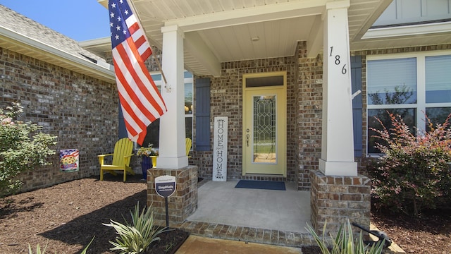 entrance to property featuring covered porch and brick siding