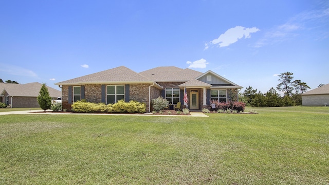 view of front of house featuring brick siding, roof with shingles, and a front yard