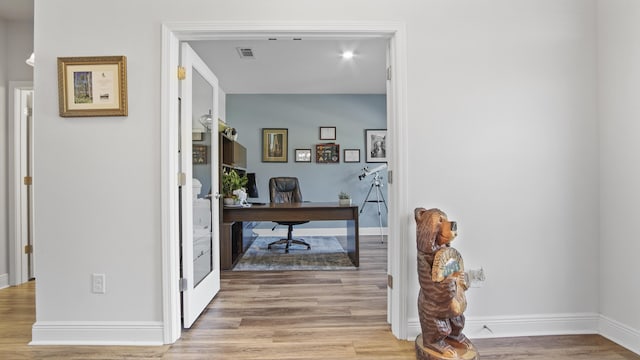 office space featuring light wood-type flooring, visible vents, and baseboards