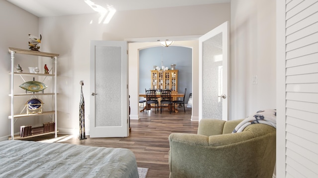 bedroom with baseboards, arched walkways, and wood finished floors