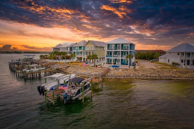 view of dock with a water view, boat lift, and a balcony