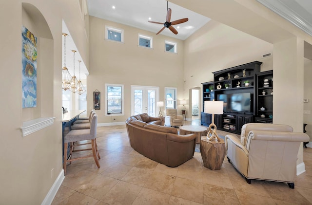 tiled living room featuring crown molding, ceiling fan with notable chandelier, and a high ceiling