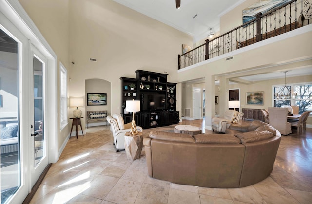 tiled living room featuring french doors, a notable chandelier, crown molding, and a towering ceiling