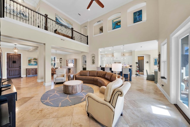 living room featuring crown molding, ceiling fan, and a high ceiling