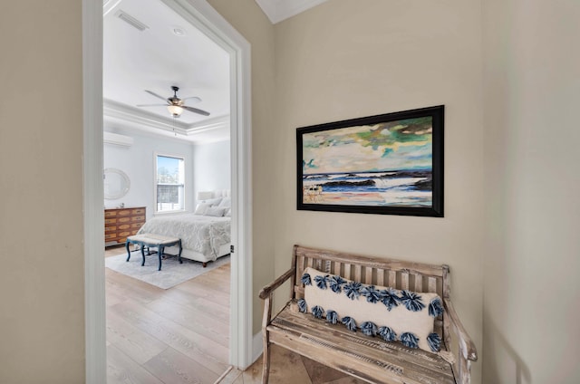 bedroom featuring ceiling fan, light wood-type flooring, ornamental molding, and a wall mounted air conditioner