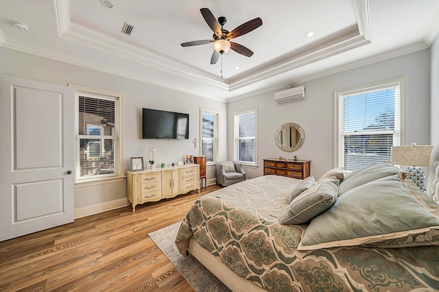 bedroom featuring ceiling fan, an AC wall unit, hardwood / wood-style flooring, and a tray ceiling