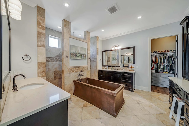 bathroom featuring tile patterned floors, vanity, crown molding, and a bathing tub