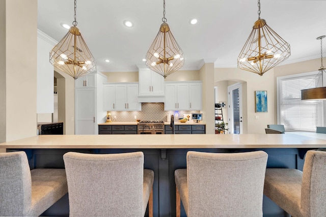 kitchen with a breakfast bar area, white cabinetry, pendant lighting, and tasteful backsplash