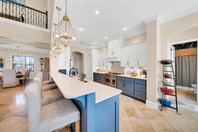 kitchen featuring white cabinetry, a kitchen breakfast bar, double oven range, a notable chandelier, and blue cabinets