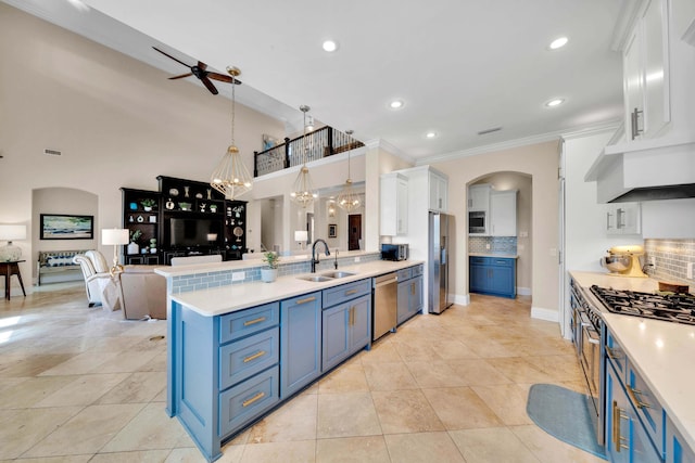 kitchen with appliances with stainless steel finishes, white cabinetry, blue cabinetry, sink, and hanging light fixtures