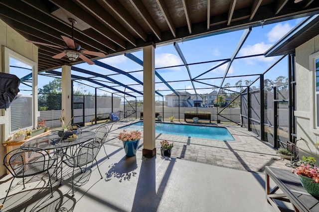 view of swimming pool with ceiling fan, a patio area, and glass enclosure