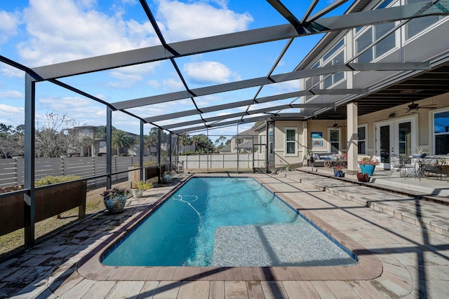 view of pool with ceiling fan, glass enclosure, and a patio