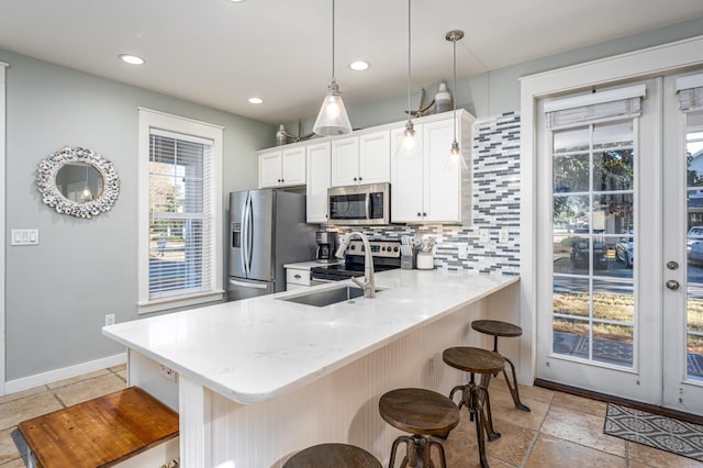 kitchen with stainless steel appliances, pendant lighting, a kitchen breakfast bar, and kitchen peninsula