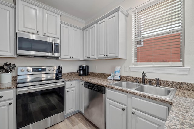 kitchen with light wood-type flooring, sink, stainless steel appliances, and white cabinetry