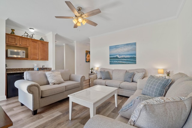 living room with ceiling fan, crown molding, and light wood-type flooring