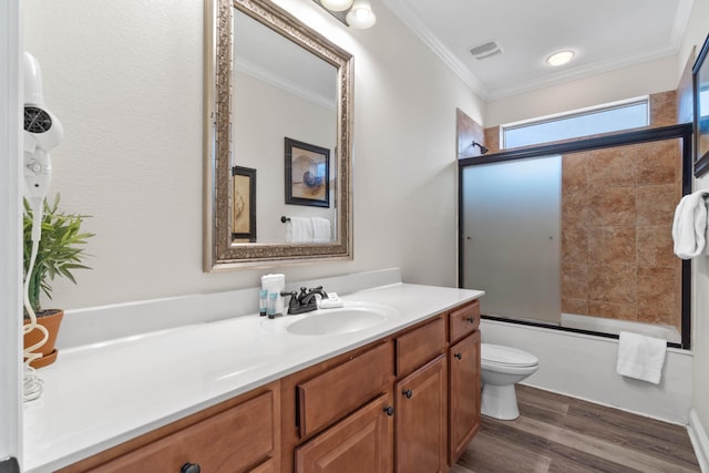 full bathroom with wood-type flooring, vanity, bath / shower combo with glass door, toilet, and crown molding