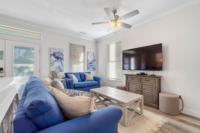 living room with light wood-type flooring, plenty of natural light, and ornamental molding