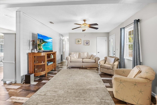 living room with a textured ceiling, ceiling fan, and dark hardwood / wood-style flooring