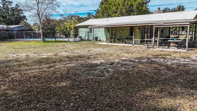 back of property with a patio area, a swimming pool, and a lawn