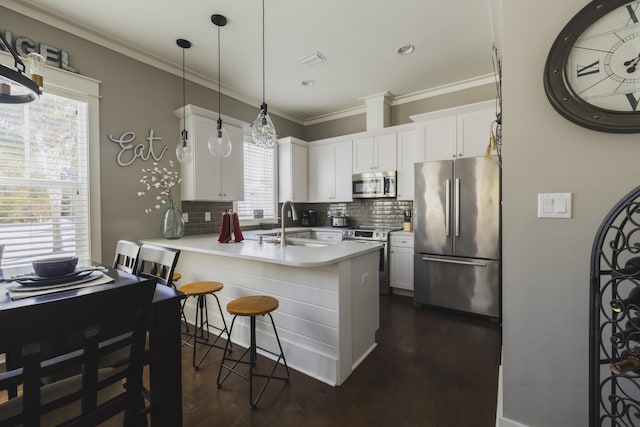 kitchen with sink, hanging light fixtures, white cabinets, and appliances with stainless steel finishes