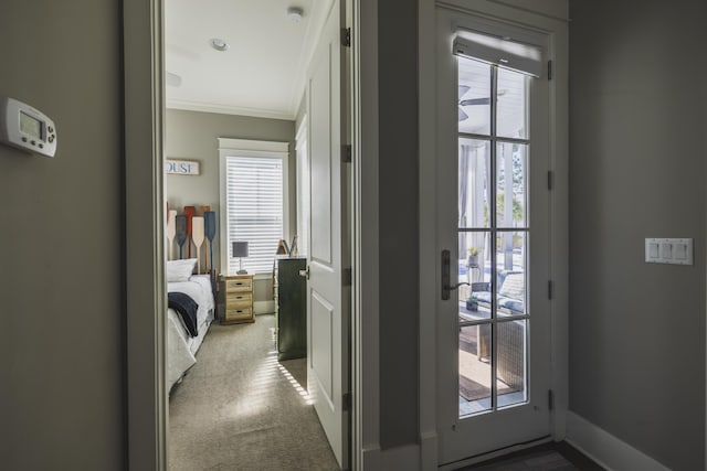 doorway to outside with crown molding and carpet flooring