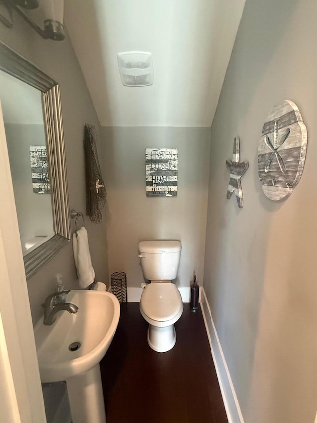 bathroom featuring lofted ceiling, sink, hardwood / wood-style floors, and toilet