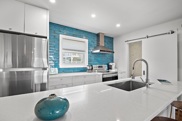 kitchen featuring stainless steel appliances, white cabinetry, sink, and wall chimney exhaust hood