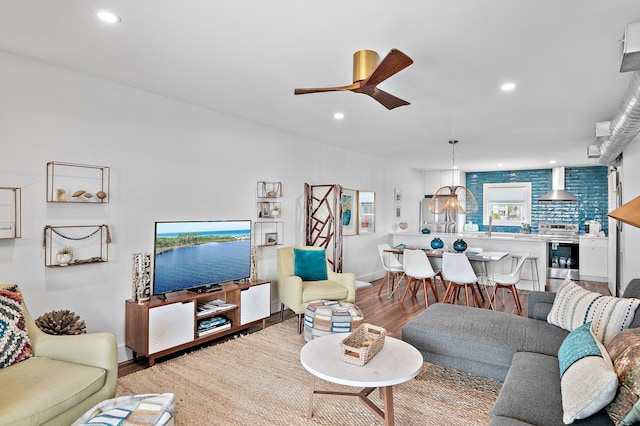 living room featuring ceiling fan, sink, and light wood-type flooring