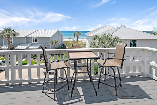 wooden terrace featuring a water view and a beach view