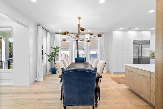 dining area featuring light hardwood / wood-style floors, plenty of natural light, and an inviting chandelier