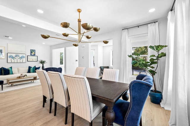 dining space with an inviting chandelier and light hardwood / wood-style flooring