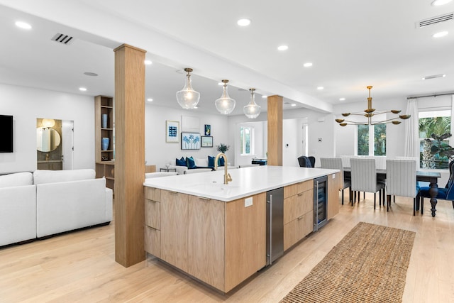 kitchen with a spacious island, decorative light fixtures, light brown cabinets, wine cooler, and sink