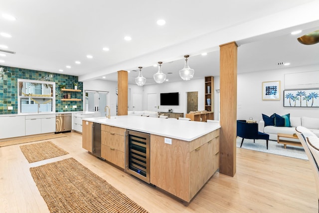 kitchen featuring dishwasher, a spacious island, pendant lighting, light brown cabinetry, and beverage cooler